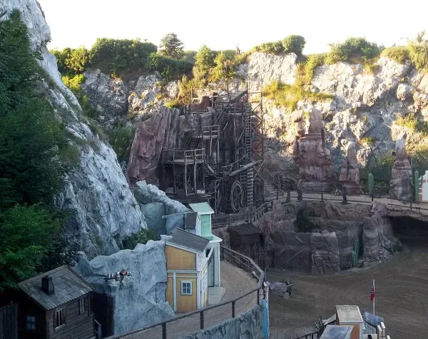 Freilichttheater in einer felsigen Landschaft mit Holzkulissen und Tribünen, vermutlich in einer historischen Darstellung.