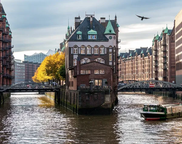Speicherstadt Hamburg, altes rotes Backsteingebäude im Kanal, umgeben von historischen Lagerhäusern an einem sonnigen Tag.