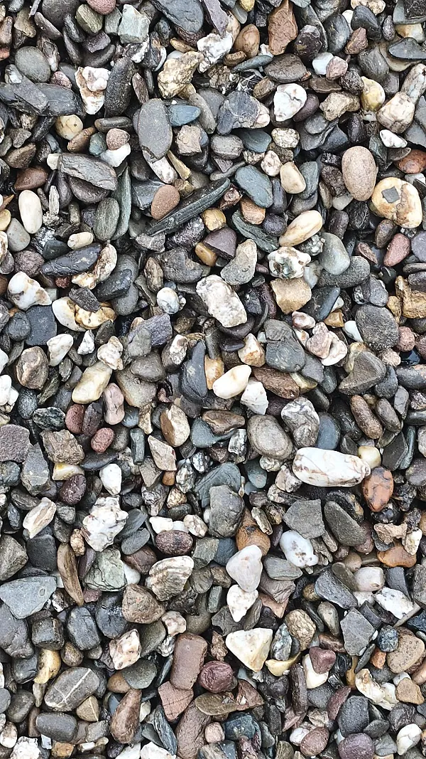 Verschiedene Kieselsteine in unterschiedlichen Größen und Farben, dicht aneinandergereiht.