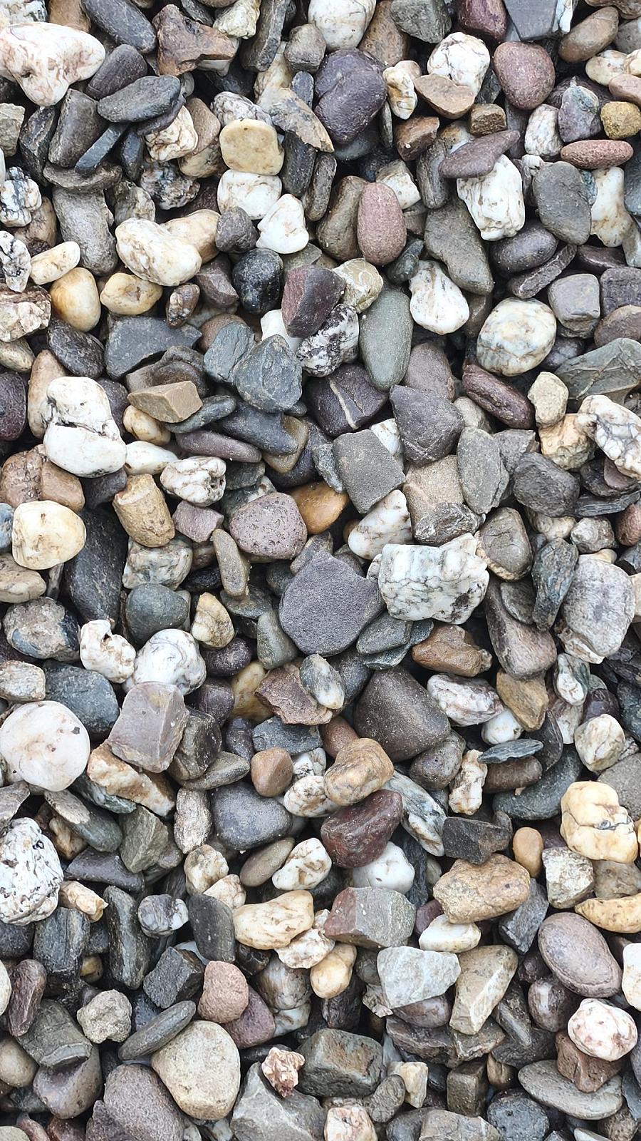Eine Ansammlung verschiedenfarbiger Drainagekies-Steine in Nahaufnahme.