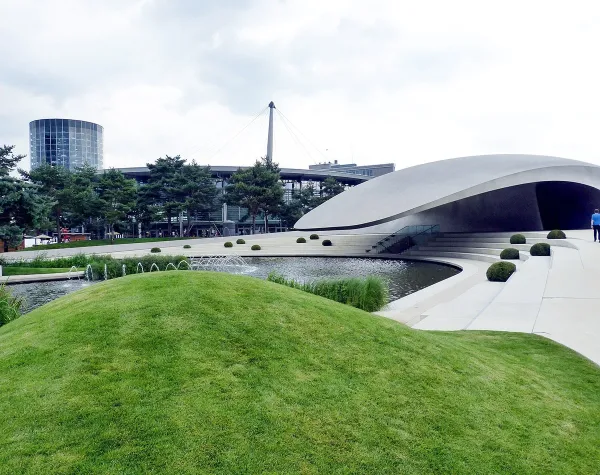 Moderne Architektur in Wolfsburg mit geschwungenem Gebäude, Rasenflächen und Wasserbecken im Vordergrund.