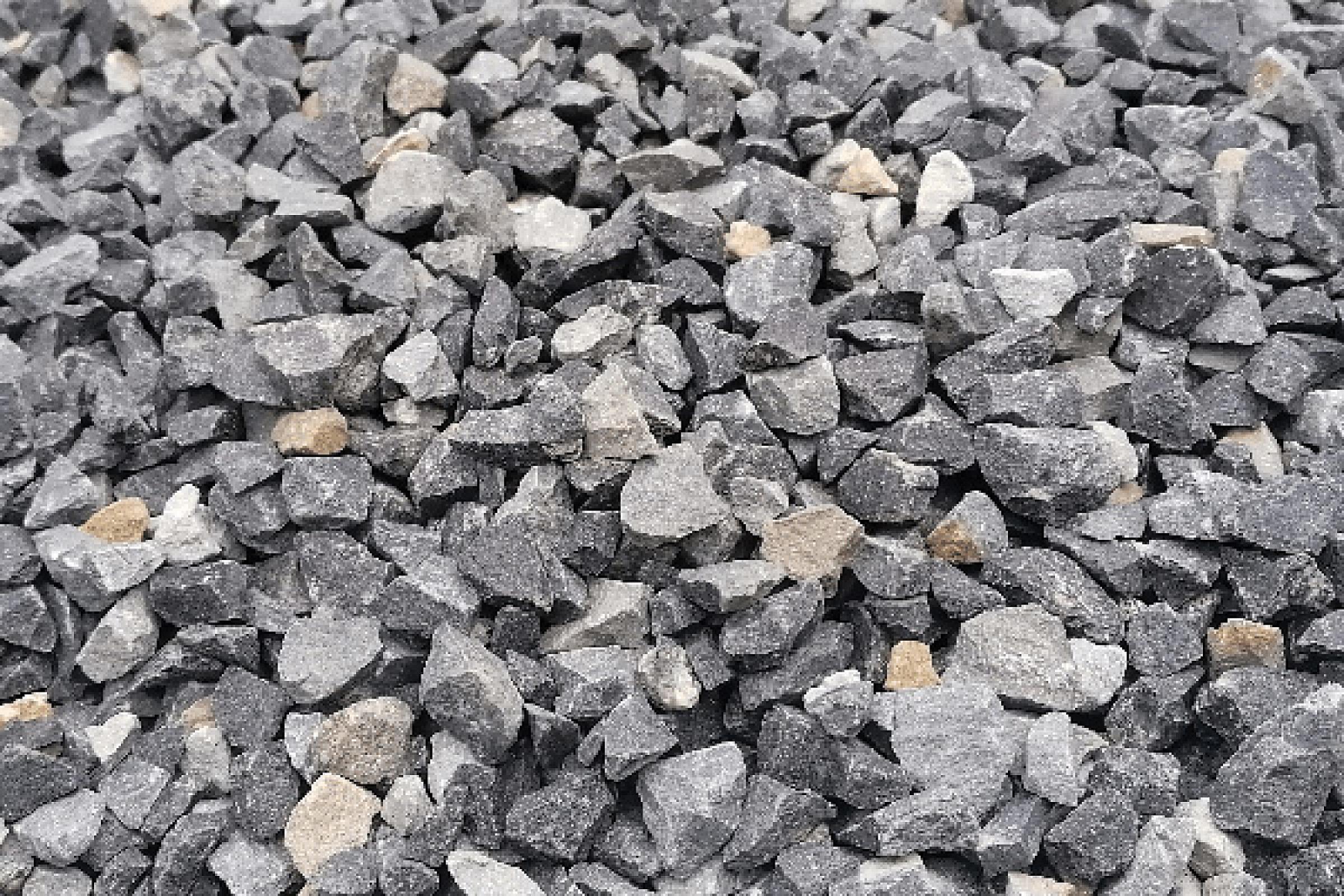 Grauer Basaltsplitt in verschiedenen Größen auf einer Fläche verstreut. Markenname: Hünten GmbH.