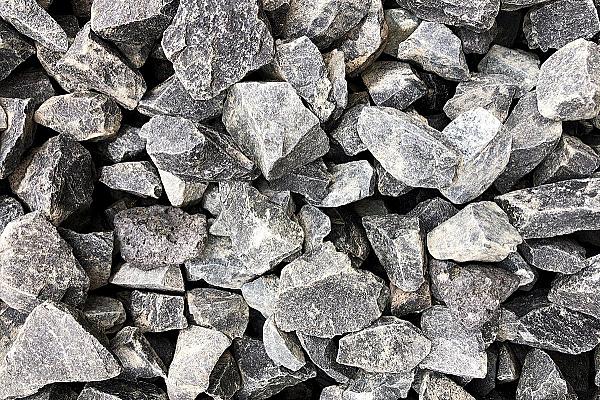 Basaltsplitt in unterschiedlichen Grautönen, bestehend aus scharfkantigen, unregelmäßig geformten Steinen.