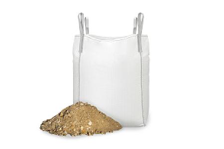 Ein großer weißer Big Bag gefüllt mit Betonkies, daneben ein kleiner Haufen Betonkies.