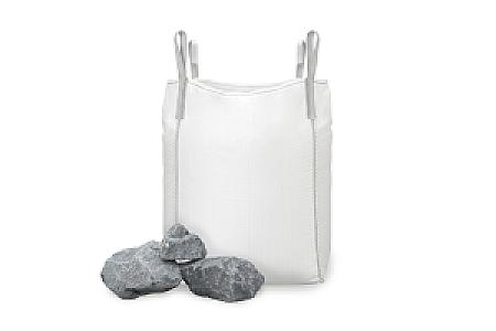Großer weißer Big Bag mit Basalt-Wasserbausteinen, einige Steine liegen daneben.