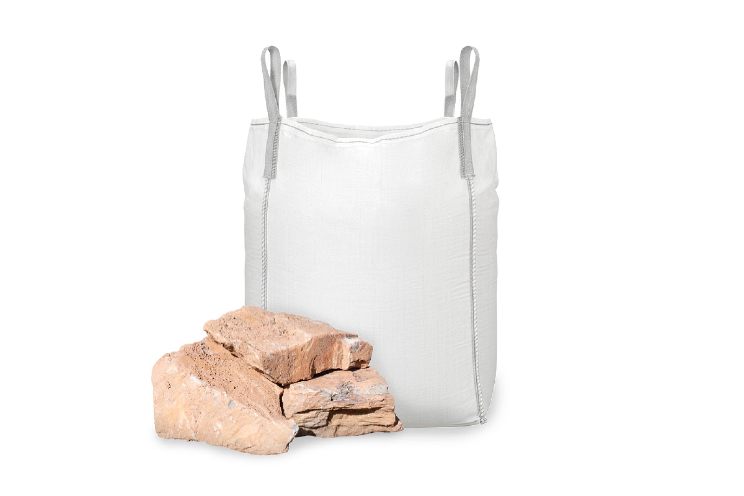 Bruchsteine aus Grauwacke vor einem weißen Bigbag-Container.