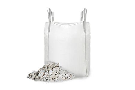 Ein weißer Big Bag gefüllt mit Kalksteinsplitt, daneben ein Haufen lose Steine.