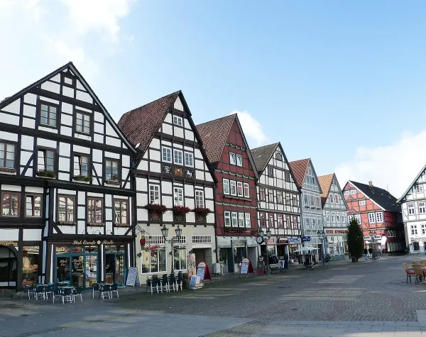 Fachwerkhäuser in einer historischen Altstadt von Schaumburg mit Straßencafés und blauem Himmel im Hintergrund.