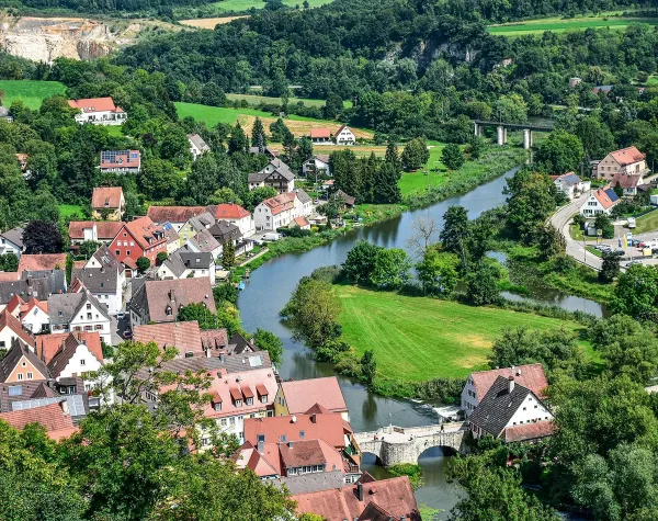 Panorama der idyllischen Stadt Harburg mit Fluss, Brücke und umgebener grüner Landschaft.