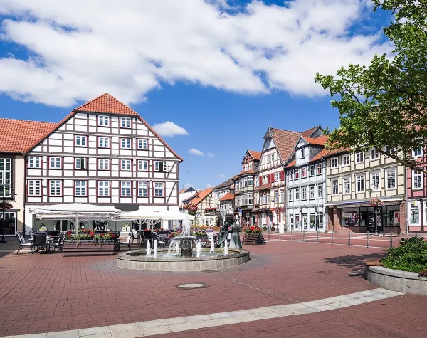 Historischer Marktplatz in Lüchow-Dannenberg mit Fachwerkhäusern und zentralem Brunnen bei sonnigem Wetter.