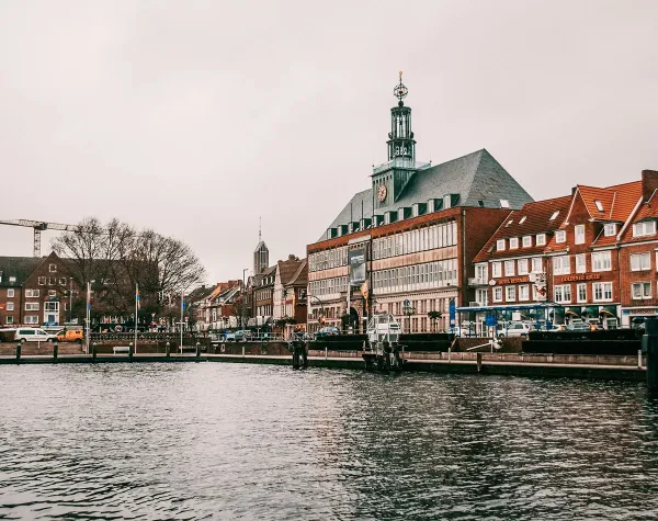 Hafen in Emden mit historischem Rathaus und umliegenden Gebäuden am Wasser.