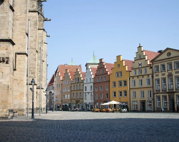 Historische Gebäude am Rathausplatz in Osnabrück mit bunten Fassaden und Straßencafé.