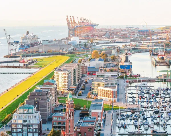 Hafen von Bremerhaven mit Schiffen, Containern und Gebäuden im Hintergrund, samt Grünflächen und Yachthafen.