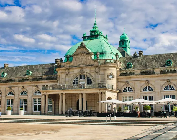 Historisches Gebäude in Minden-Lübbecke mit grünem Kupferdach und Terrasse unter blauen Himmel mit Wolken.