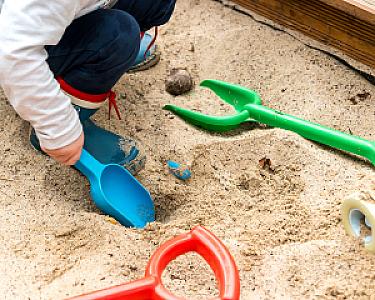 Kind spielt mit bunten Schaufeln im Hellerwald-zertifizierten Spielsand.