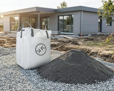 Bigbag mit Lavasand der Marke Hellerwald auf Kiesboden vor modernem Gebäude.