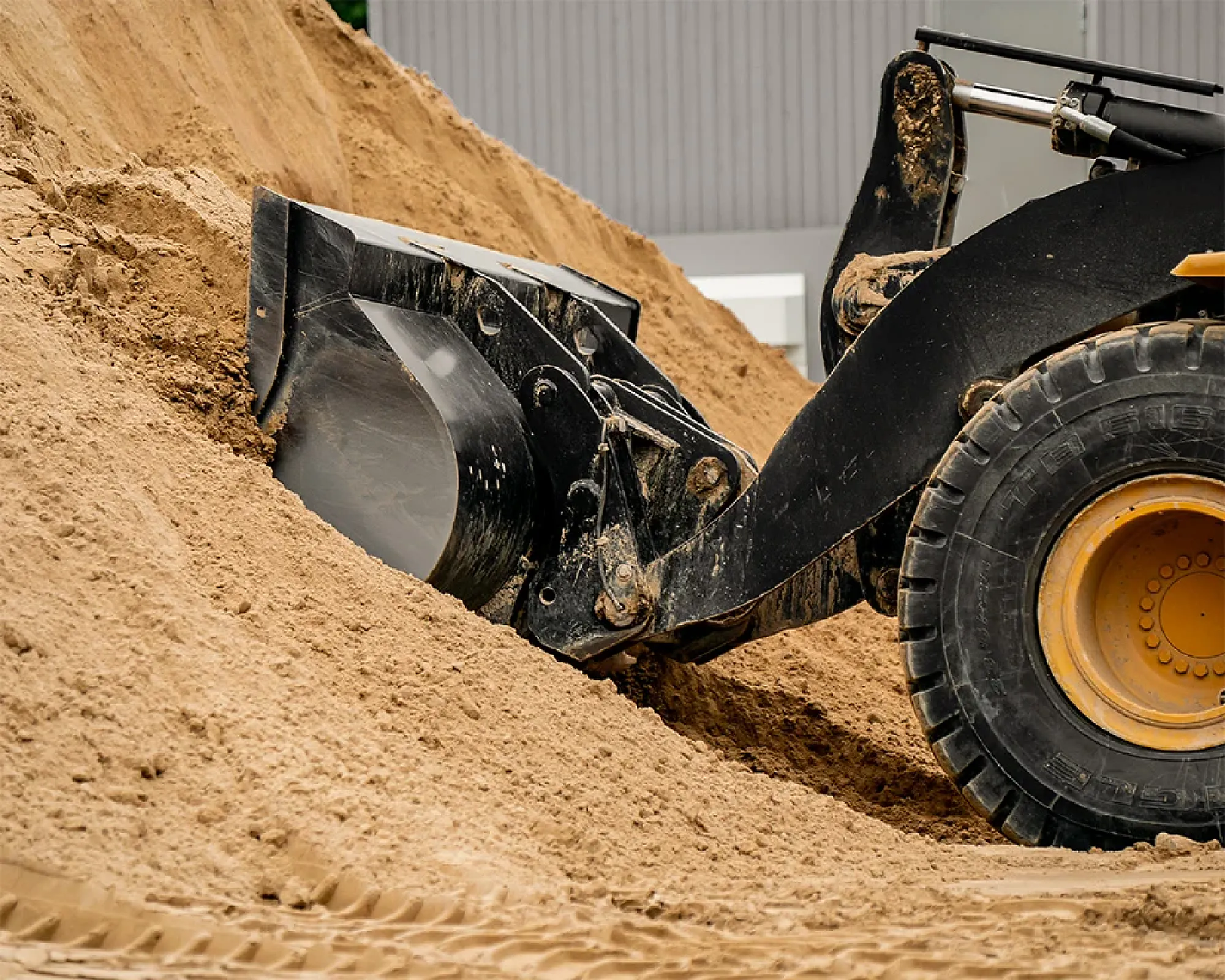 Bagger schaufelt gewaschenen Mauersand in einer industriellen Umgebung.