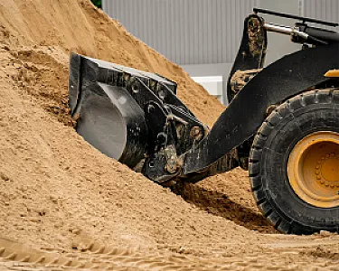 Bagger schaufelt gewaschenen Mauersand in einer industriellen Umgebung.