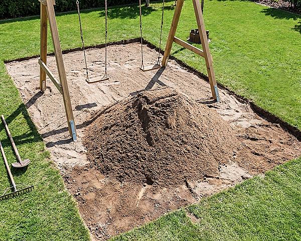 Zertifizierter Spielsandhaufen unter Holzschaukelgerüst im Garten.