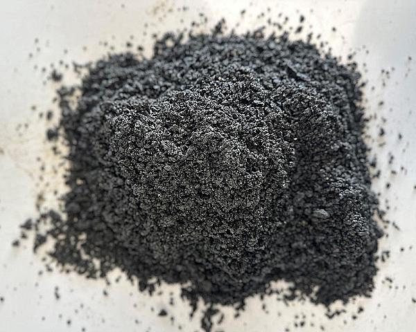 Ein Haufen feiner, dunkler Basaltsand von Volz und Herbert GmbH auf hellgrauem Hintergrund.