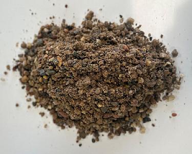 Ein Haufen Estrichsand mit unregelmäßigen Körnungen auf weißem Hintergrund.