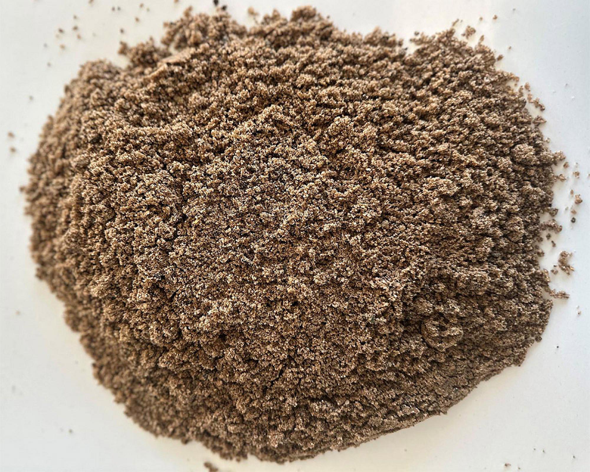 Ein Haufen feiner Rohrsand auf einer hellen Oberfläche, bereit für die Verwendung in Bauprojekten.