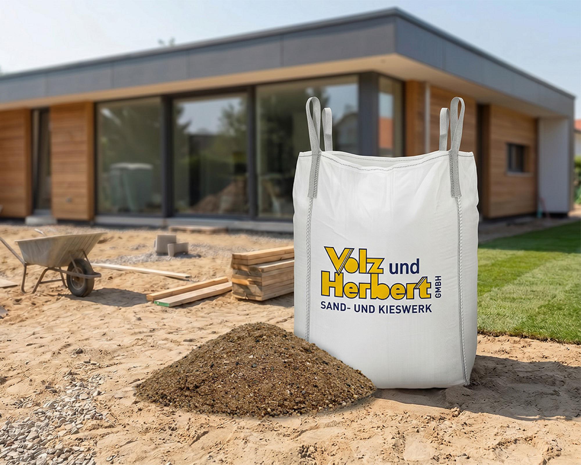 Big Bag von Volz und Herbert GmbH, gefüllt mit sand, auf Baustelle neben moderner Holzhausarchitektur.