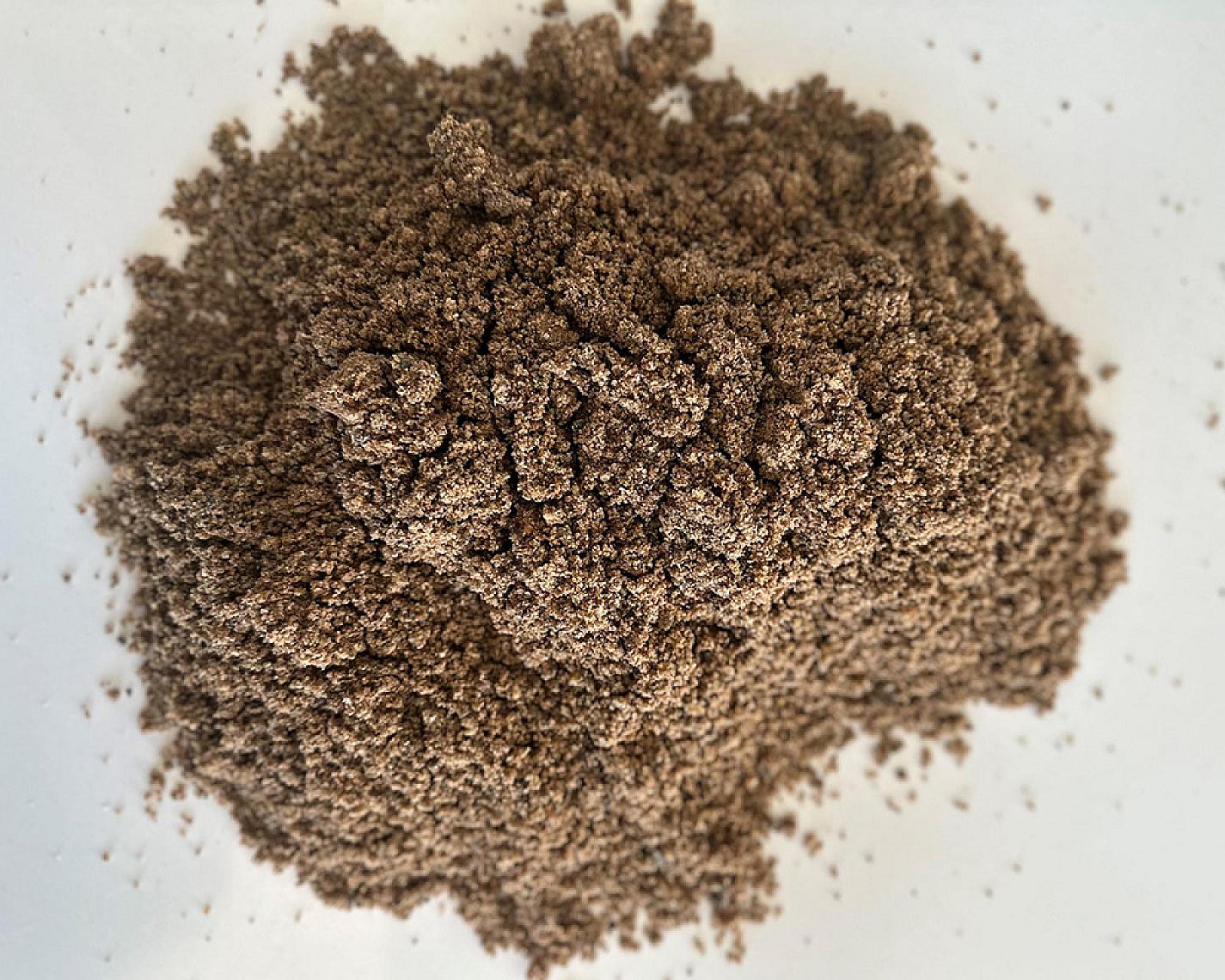 Ein Häufchen gewaschener Paddocksand auf einer weißen Oberfläche.