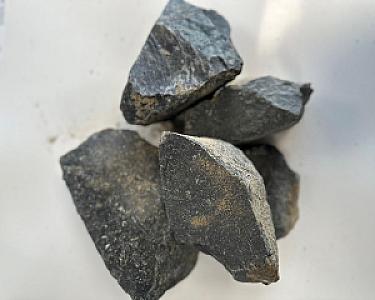 Basaltsplitt 8-16 mm, dunkle Steine auf hellem Hintergrund, von Volz und Herbert GmbH.