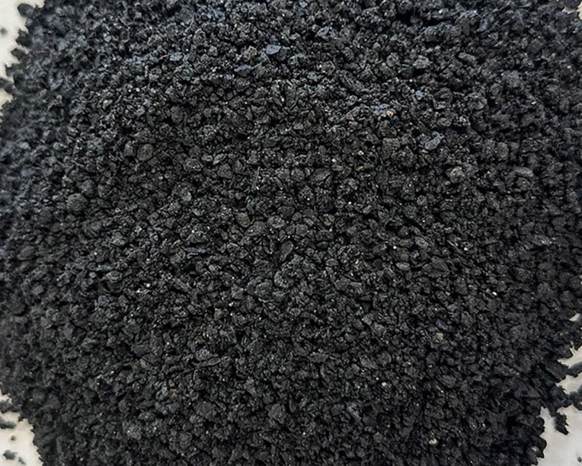 Haufen schwarzer Fugensplitt von Volz und Herbert GmbH, grobkörnige Textur.