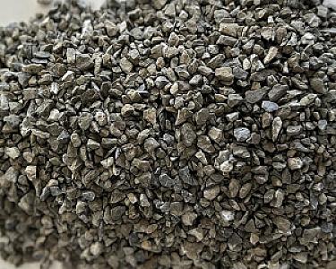 Haufen grauer Kalksteinsplittkiesel von Volz und Herbert GmbH auf heller Oberfläche.