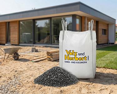 Big Bag mit Pflastersplitt von Volz und Herbert GmbH vor modernem Neubau auf Baustelle.
