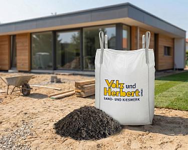 Ein Big Bag von Volz und Herbert GmbH mit Rollrasenerde steht auf einer Baustelle vor einem modernen Haus.