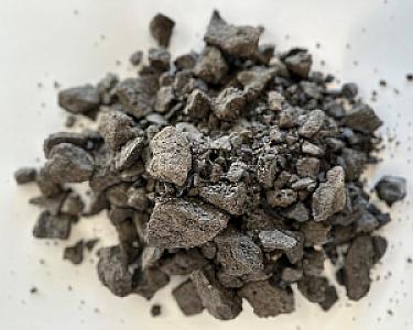 Haufen von grobem, grauem Basaltschotter auf weißem Hintergrund.
