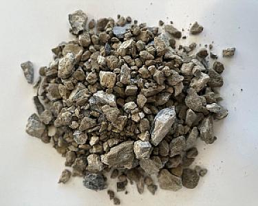 Haufen Kalksteinschotter in verschiedenen Größen auf hellem Hintergrund.