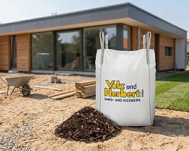 Großer Big Bag mit grobem Rindenmulch von Volz und Herbert GmbH auf Baustelle vor modernem Haus.