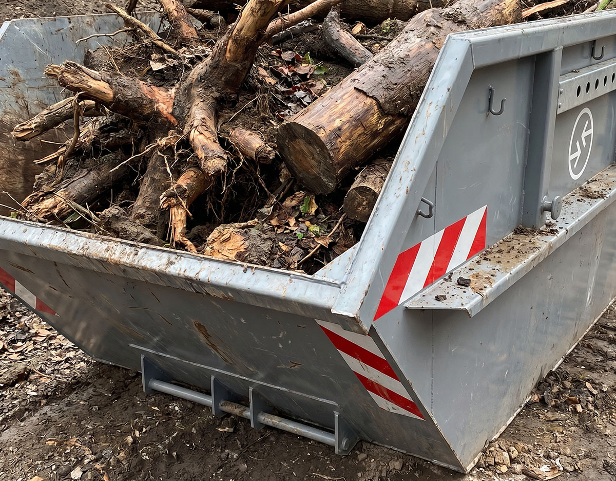 Container gefüllt mit Baumstämmen, Wurzeln und Stubben, geeignet für Gartenabfälle.