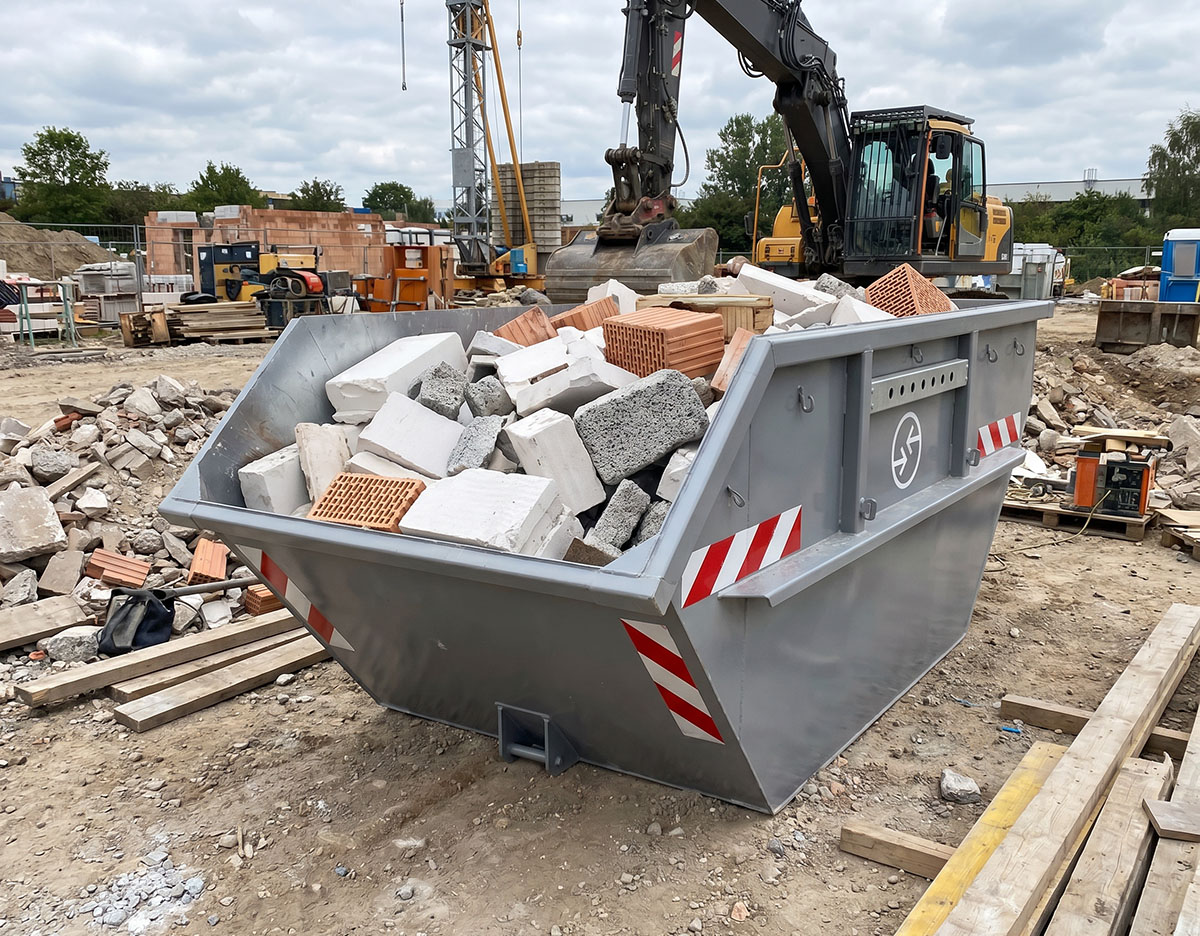 Container mit Leichtbaustoffen gefüllt, auf einer Baustelle, umgeben von Maschinen und Baumaterialien.