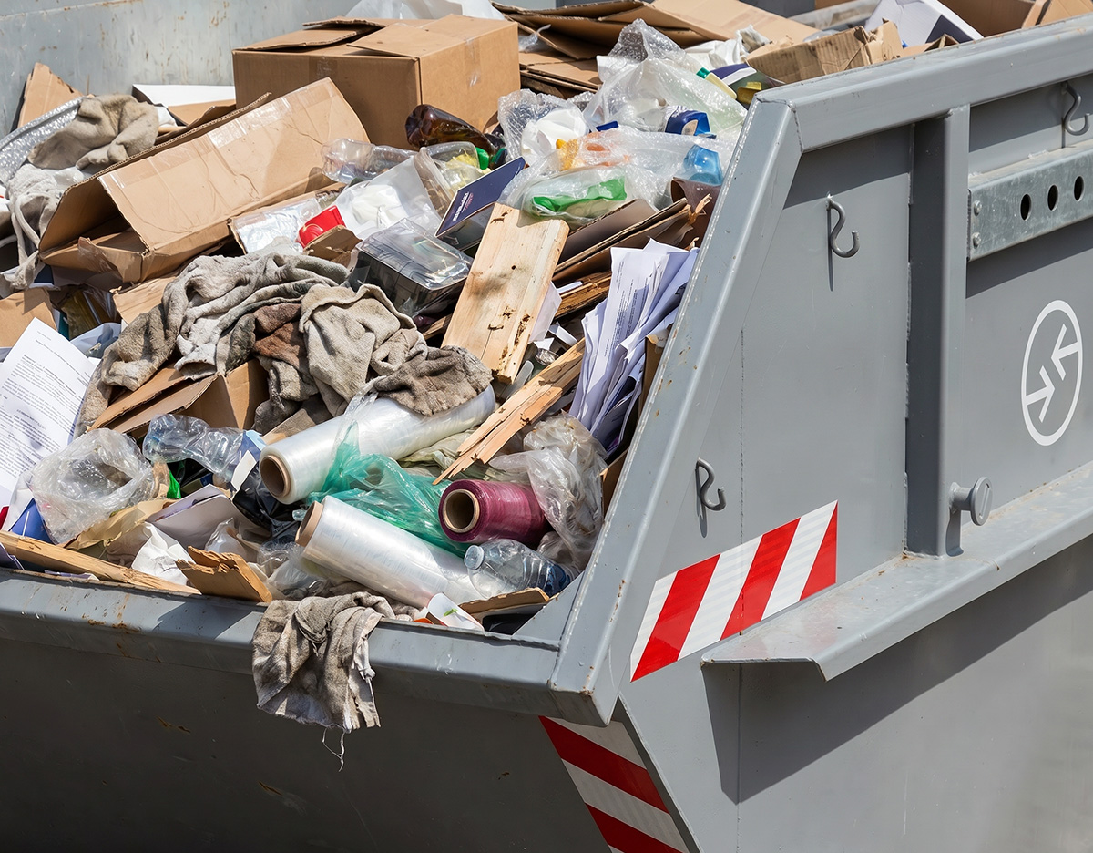 Großer Gewerbeabfall-Container, gefüllt mit Kartons, Folien und gemischtem Recyclingmaterial.