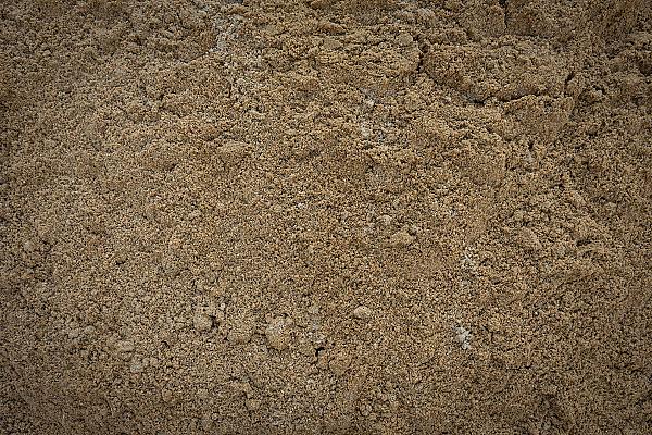 Gewaschener Sand in Nahaufnahme, beige Farbe, gleichmäßige Körnung, unter strahlendem Licht.