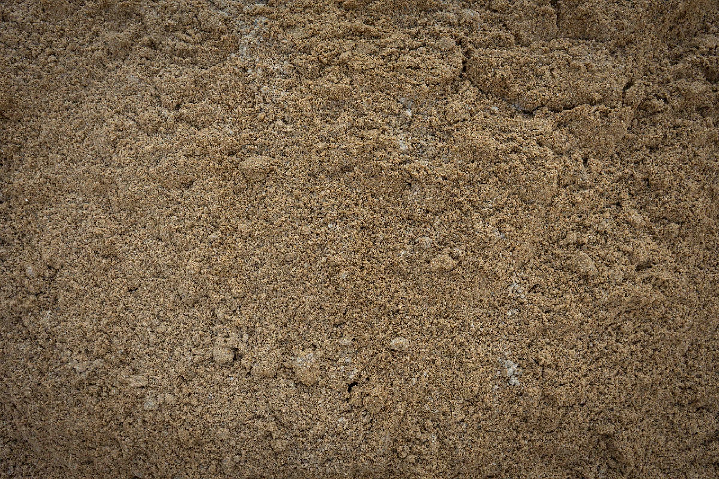 Gewaschener Sand in Nahaufnahme, beige Farbe, gleichmäßige Körnung, unter strahlendem Licht.