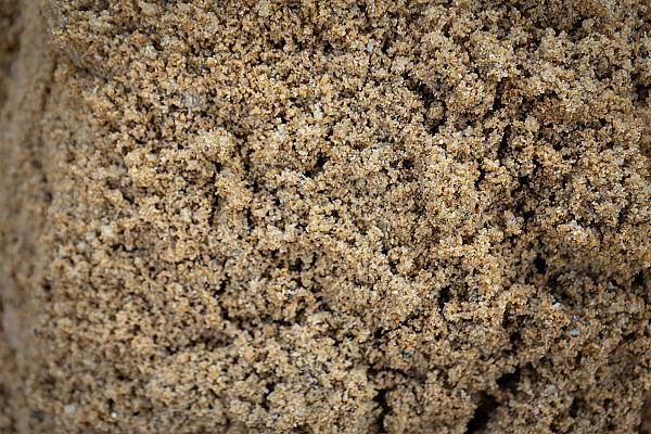Gewaschener Sand in Nahaufnahme, beige Farbe, grob strukturiert, verwendet für Bau und Dekoration.