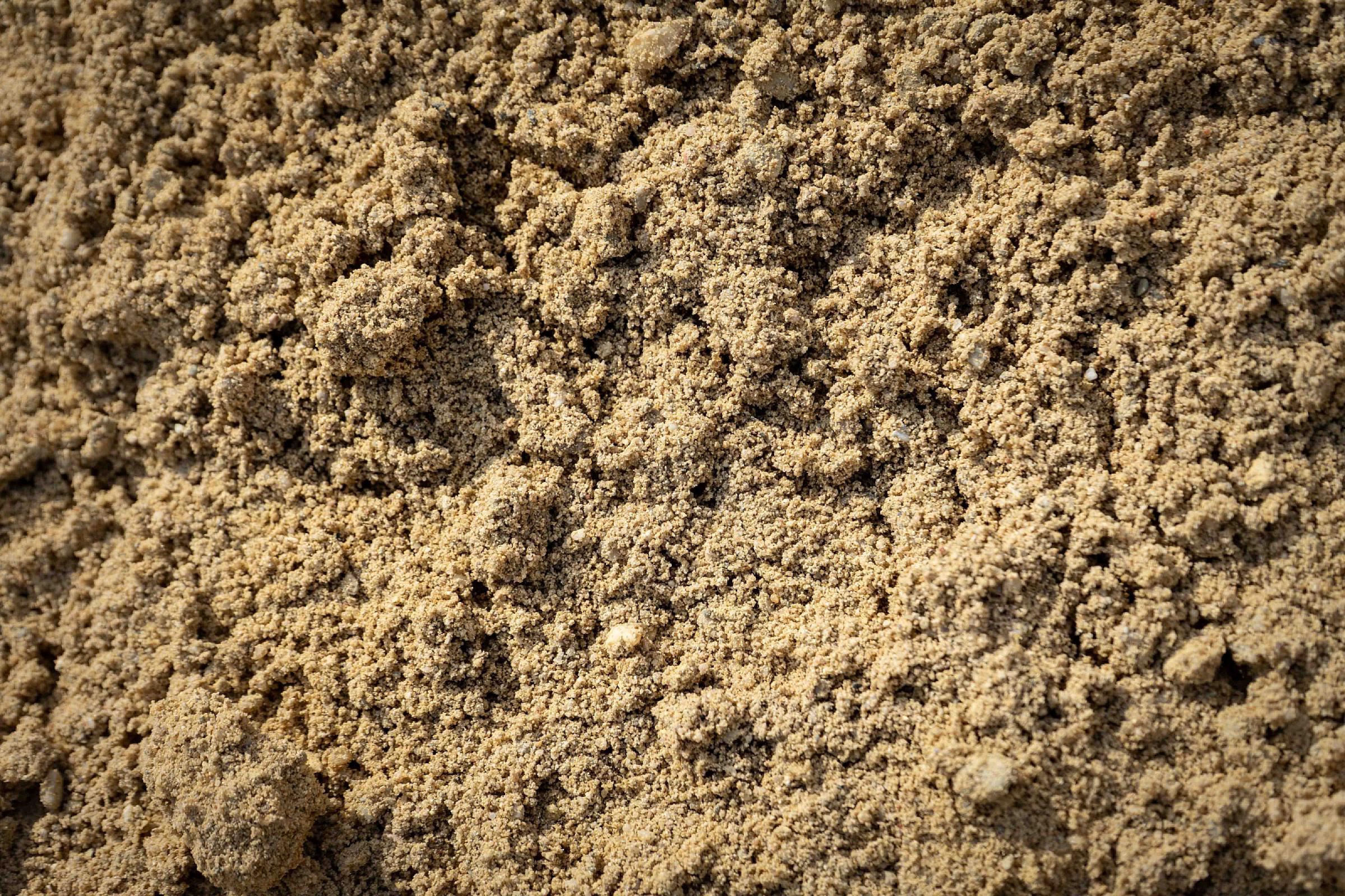 Nahaufnahme von gewaschenem Sand der HTA GmbH aufgeschüttet, beige und grobkörnig.