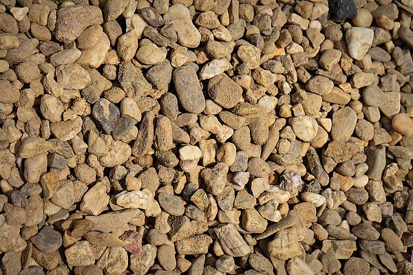 Rheinkies gewaschen in verschiedenen Größen und Farben, verteilt auf einer Fläche.