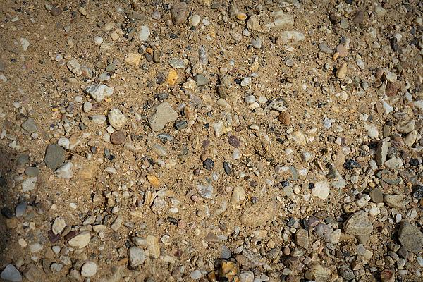 Betonkies von HTA GmbH mit unterschiedlichen Kieselsteinen auf einer sandigen Oberfläche.