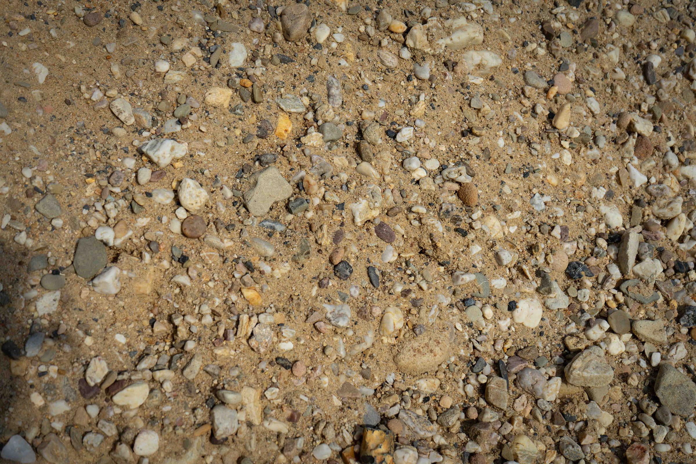 Betonkies von HTA GmbH mit unterschiedlichen Kieselsteinen auf einer sandigen Oberfläche.