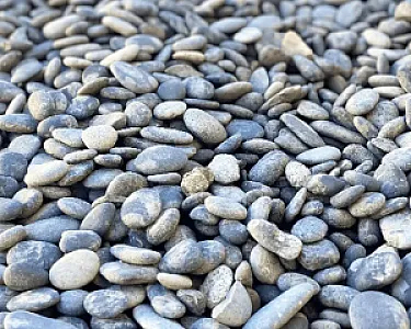 Schwarze Rundkieselsteine in verschiedenen Größen und Formen, auf einem Haufen arrangiert.