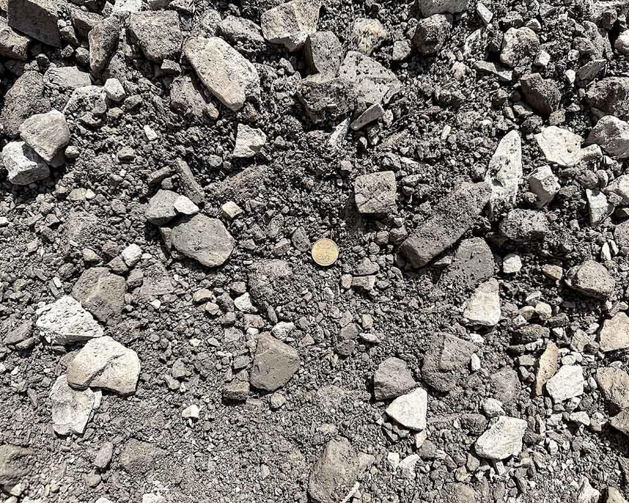 Haufen aus grauem Natursteinmineralgemisch, verschieden große Steine unverändert in losem Verbund.