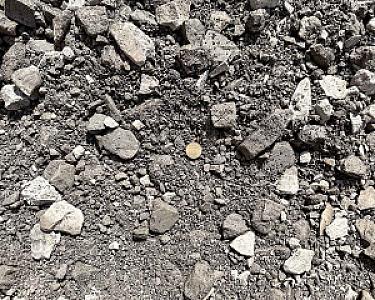 Haufen aus grauem Natursteinmineralgemisch, verschieden große Steine unverändert in losem Verbund.