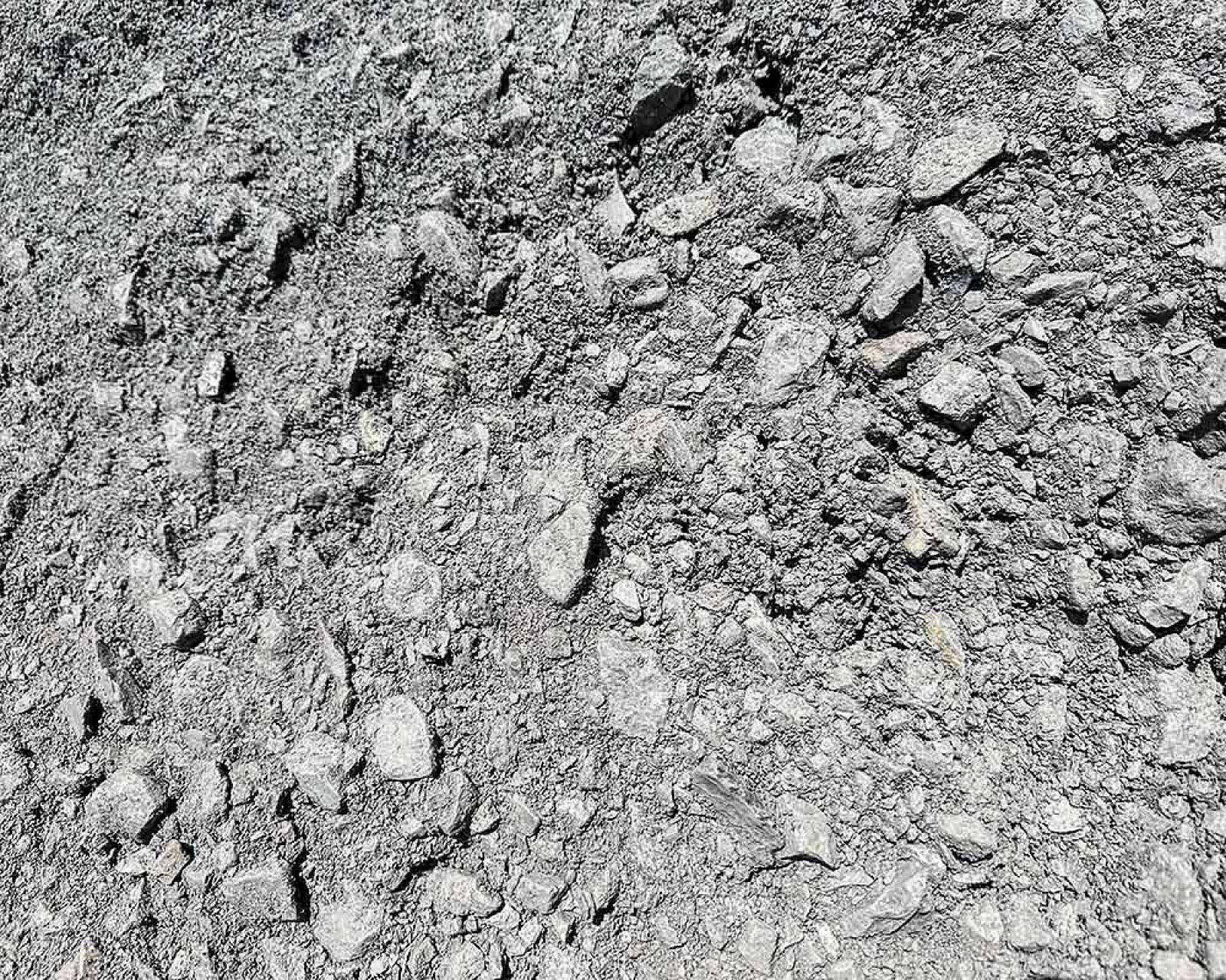 Haufen von grobem Natursteinmineralgemisch, verwendet als Frostschutzschotter, gräuliche Steintextur sichtbar.
